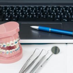 Zahnspangenmodell neben Laptop und Behandlungsinstrumenten