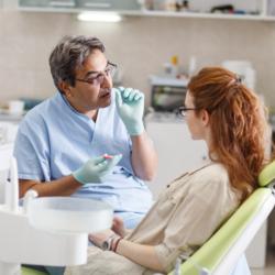 Zahnarzt erklärt Patientin die Behandlung