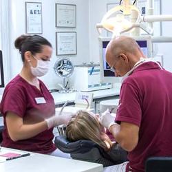 Zahnarzt behandelt Patienten mit Assistentin
