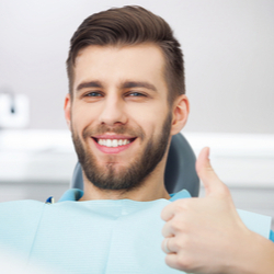 Patient auf Zahnarztstuhl zeigt Daumen hoch