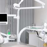 Behandlungszimmer, grauer Behandlungsstuhl, Tablett mit Geräten, Bildschirm
